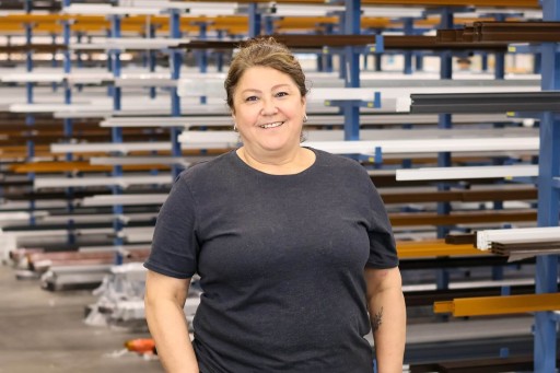 Claudia Krug Frau in einem industriellen Lager mit Regalen im Hintergrund