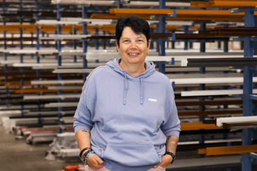 Margit Heinz Frau mit kurzem Haar und Hoodie lächelt in einer Industriehalle